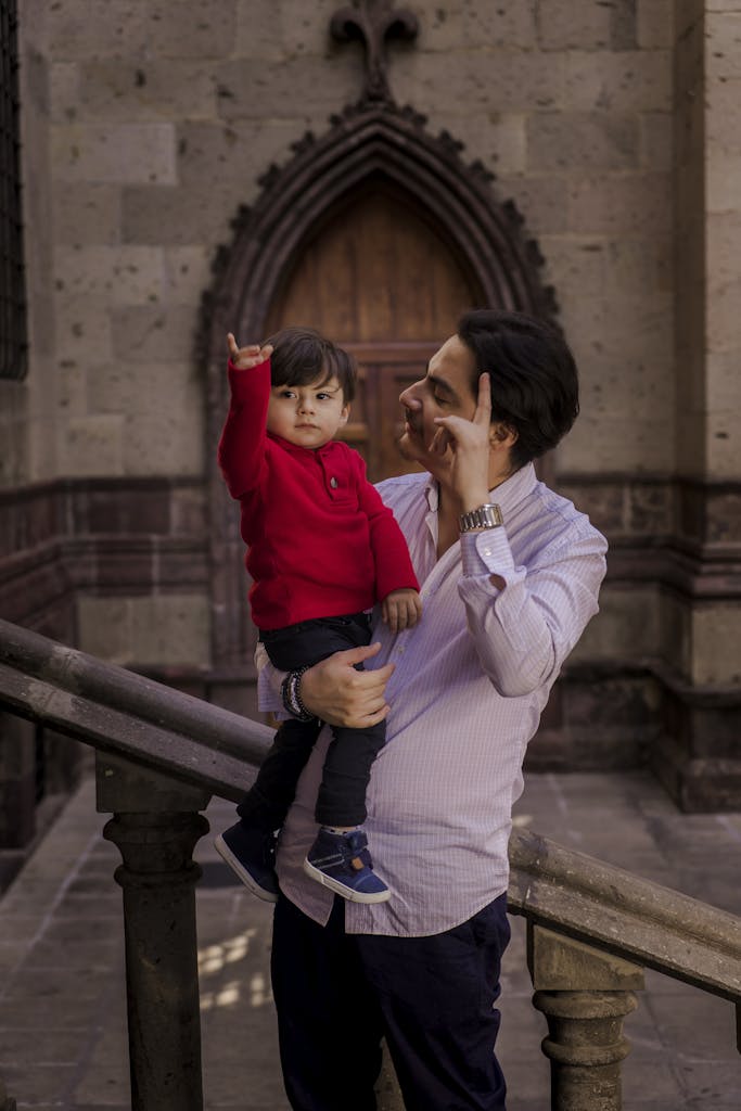 Warm moment between a father and son in an outdoor setting by a historic stone wall.